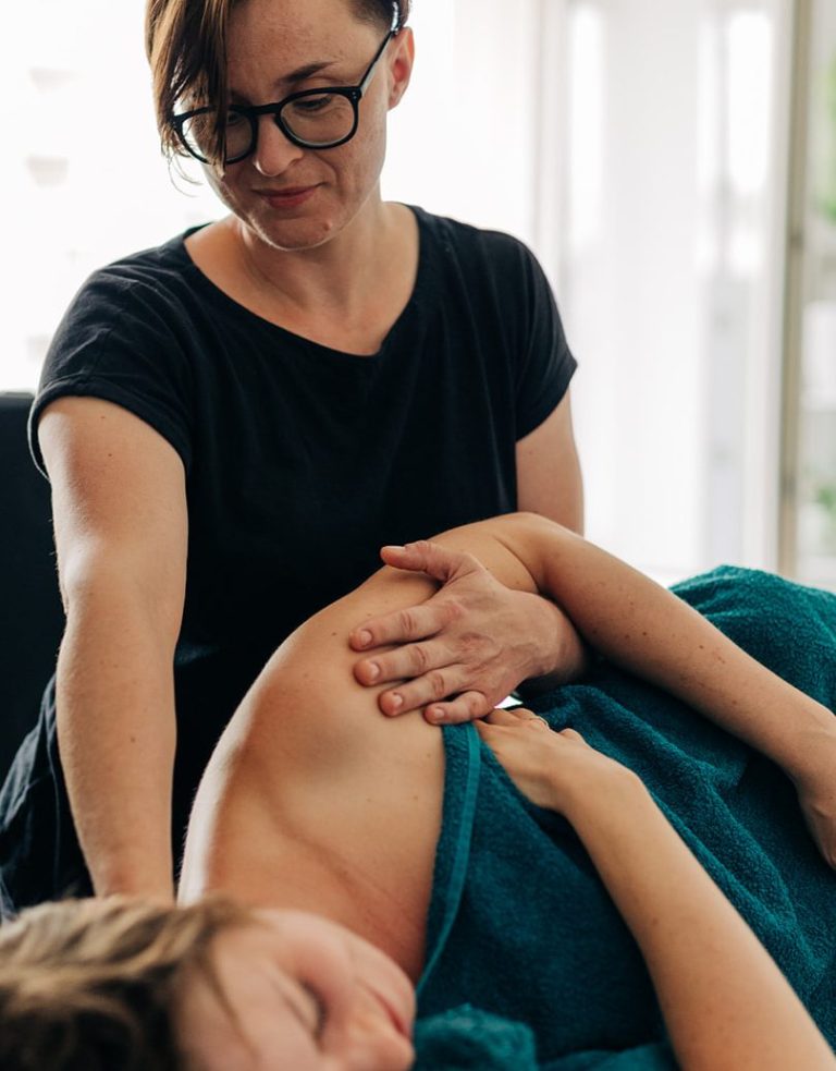 Soft tissue therapist providing mobile  sports massage treatment for shoulder tension at a client’s home in South West London.